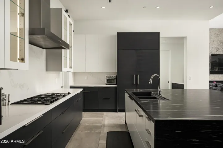 Oversized kitchen island showcasing waterfall-edge leathered granite countertops with abundant storage on both sides, blending striking design with everyday functionality.
