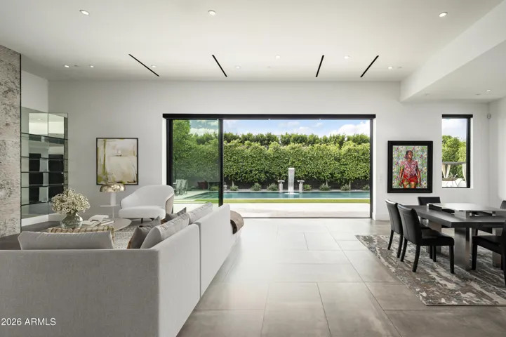 The great room flows effortlessly to the outdoors through expansive sliding doors, revealing low-maintenance landscaping, a zero-edge PebbleTec pool with water feature, a covered patio with built-in grill, and an additional side yard for added flexibility and enjoyment.