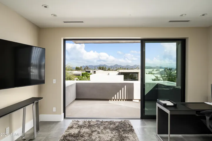 The upper level offers a versatile en suite retreat—ideal as a bedroom, office, or additional lounge—featuring a private deck with picturesque views of the McDowell Mountain Range and Mummy Mountain.
