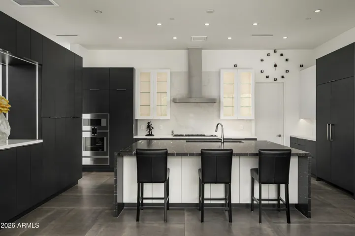 Open-concept kitchen seamlessly connected to the great room, featuring LED-lit cabinetry and an oversized island with generous storage on both sides. Premium Gaggenau appliance suite includes dual beverage coolers, gas cooktop, microwave, oven, warming drawers, and a full-size refrigerator and freezer—designed for both everyday living and elevated entertaining.