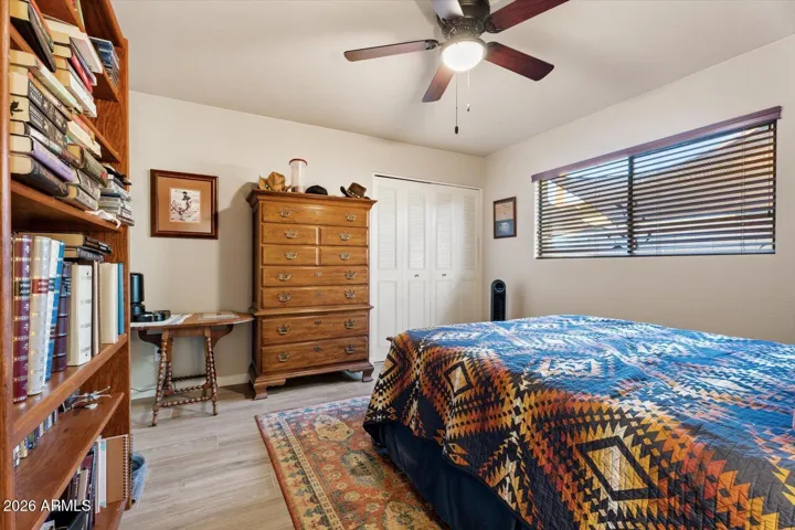 First guest bedroom featuring tile flooring, built out closest and wood blinds for privacy.