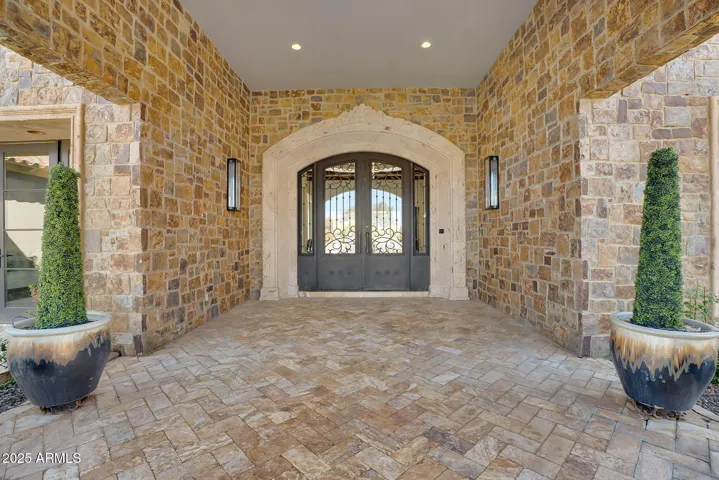 Sophisticated entrance featuring grand double doors and detailed stone design, highlighting the home’s luxurious character.