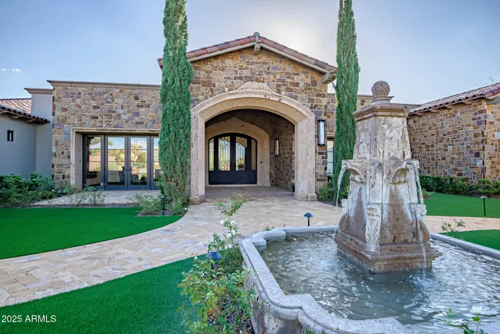 Grand entrance featuring Italian cypress, a serene fountain, and inviting architectural details — the perfect first impression.