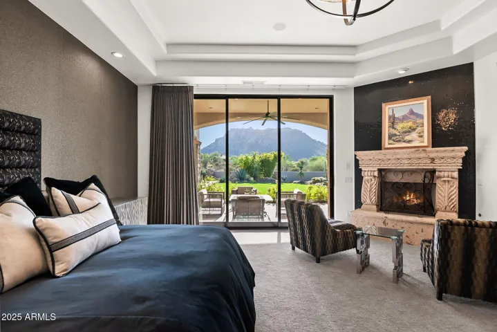 Luxury primary retreat featuring a sitting area, cantera stone fireplace, and seamless connection to outdoor living with views of Troon Mountain.