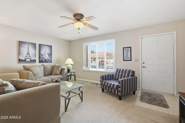 Neutral toned front living room with north-facing window with plantation shutters.
