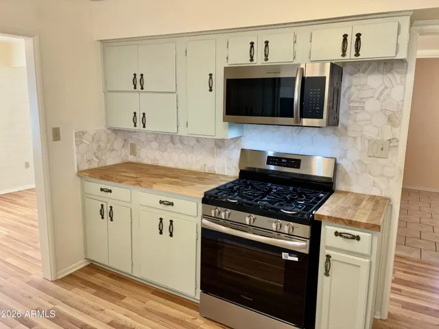 Remodeled Kitchen featuring Stunning Tile Backsplash, Natural Wood Countertops, and New Stainless Steel Appliances
