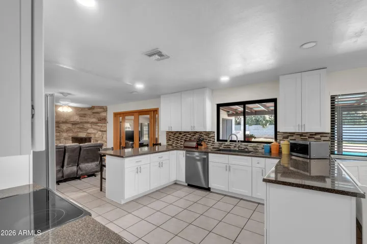 The kitchen has been opened up and refreshed — white cabinetry, updated counters, and a sink window that brings in natural light.