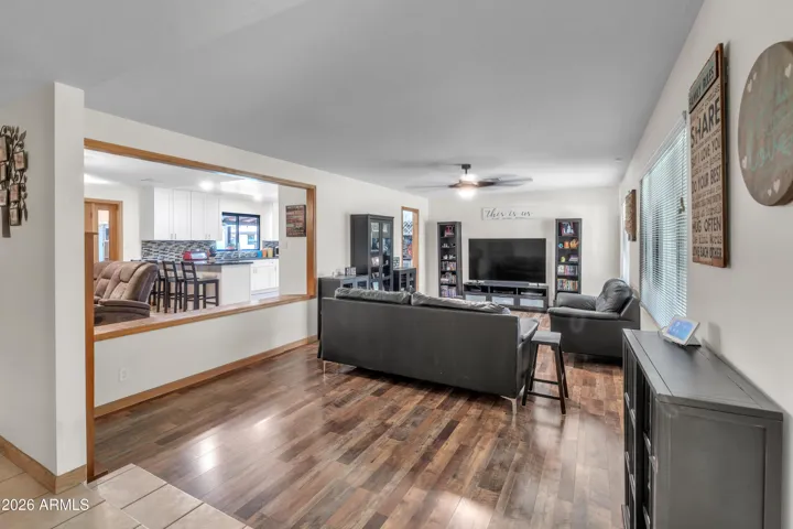 Main living room with newer flooring, step-down design, and connection to the fireplace room and kitchen.