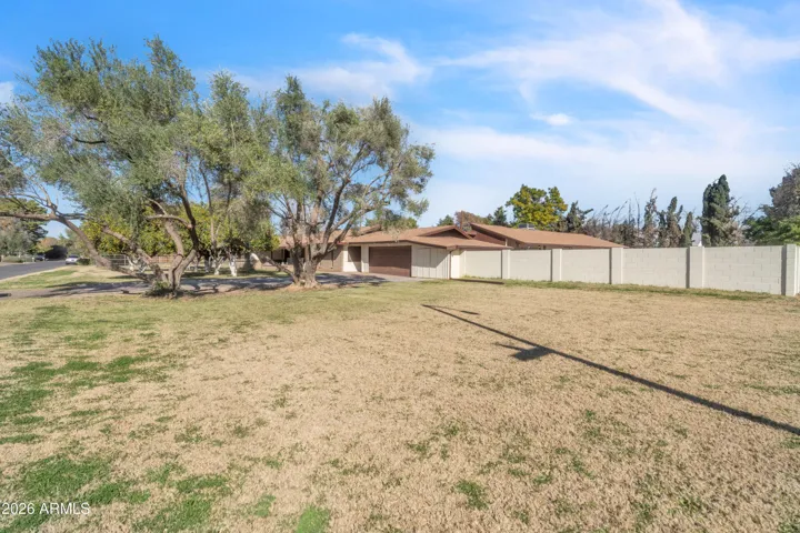 Wide corner view showcasing the generous front lawn, open space, and approach to the main driveway.