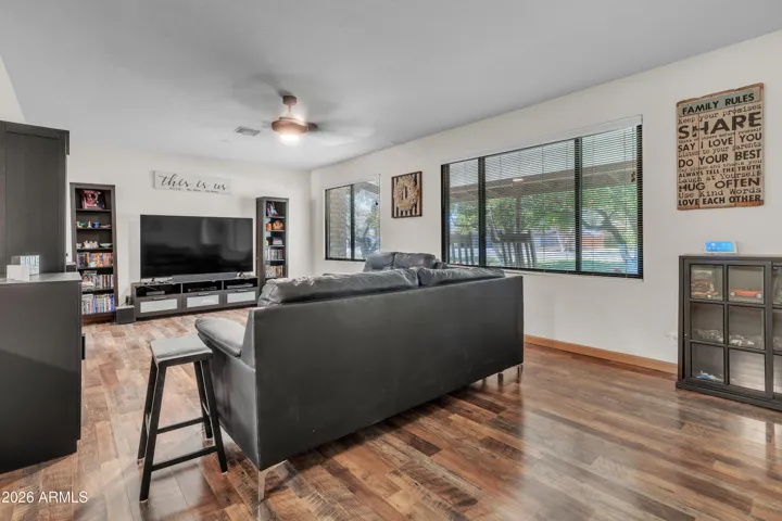 A living room with a view — step-down design, newer flooring, and a front window looking out toward the citrus orchard.