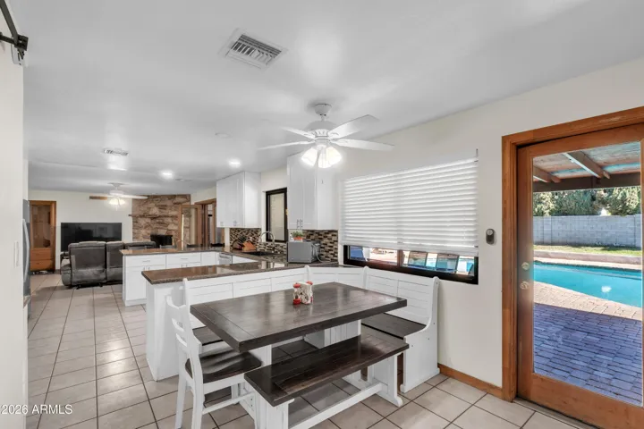 A light-filled breakfast nook that connects beautifully to the outdoor lifestyle — large window, glass door, covered patio, and pool just beyond.