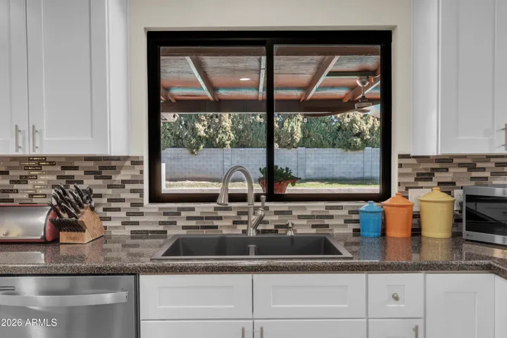 Even at the sink, the view delivers — pool, covered patio, and the kind of backyard that makes this property feel special.