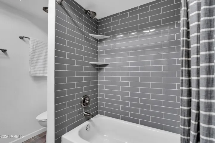 A polished hall bath detail — gray subway tile to the ceiling, a fresh shower/tub combo, and a clean, updated feel.