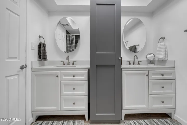 A refreshed hall bath with the function buyers appreciate — dual sinks, bright finishes, and built-in storage between the vanities.
