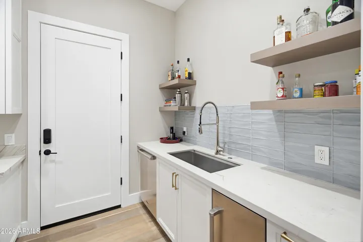 Entrance from 2 car garage into Butlers Pantry with deep sink, dishwasher and ice maker