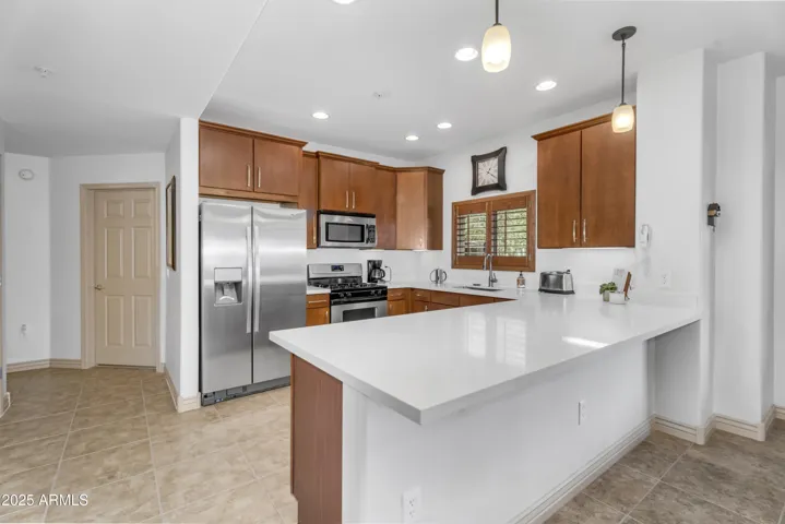 Bright and spacious kitchen in this Phoenix condo features stunning quartz countertops, pendant lighting, and stainless steel appliances—perfect for entertaining in Toscana at Desert Ridge.
