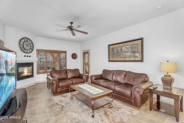 This welcoming living area features a tiled floor, gas fireplace, and plantation shutters—combining warmth and energy-efficient comfort in this Desert Ridge condo.