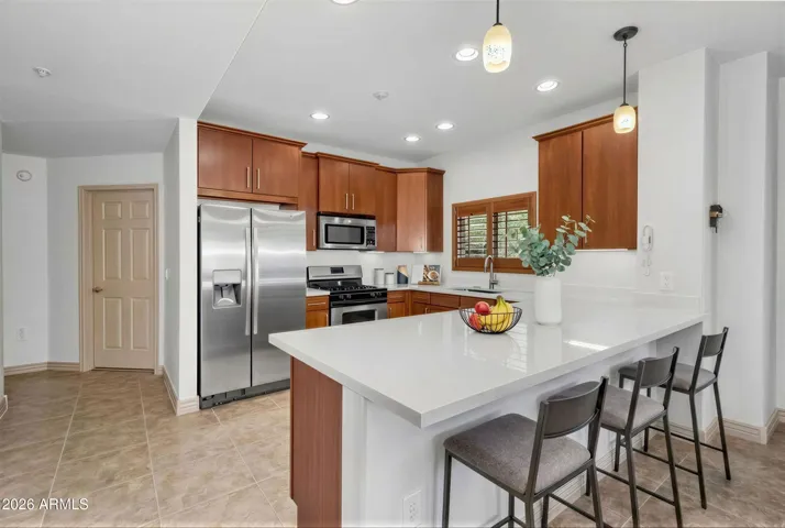 This modern kitchen boasts rich cabinetry, stainless steel appliances, and gleaming quartz countertops. A large center island with seating creates the perfect spot for casual dining or entertaining, all while enjoying a functional and stylish design.