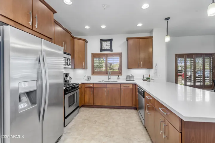 The beautifully updated kitchen boasts quartz counters, gas range, and an extended peninsula with seating—ideal for hosting or casual meals in sunny Phoenix.