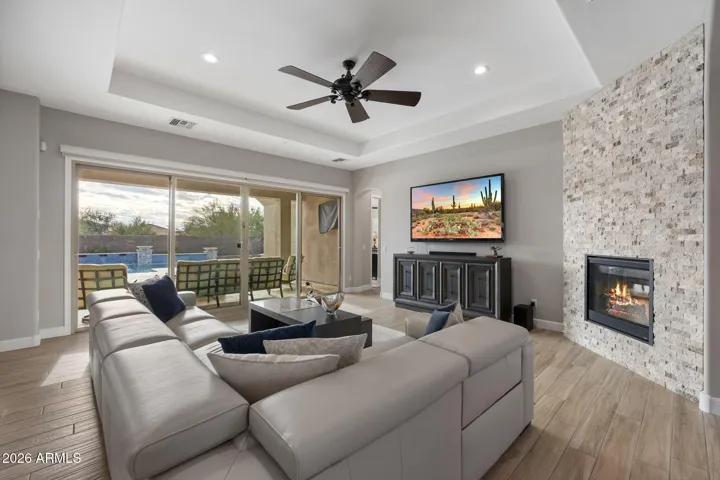 Open great room with sliding glass doors overlooking resort-style pool and spa, offering seamless indoor-outdoor Arizona living.