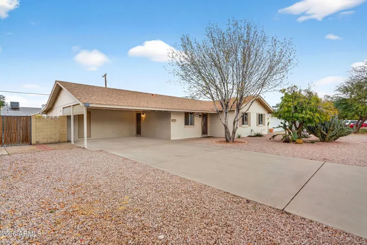 Spacious driveway with covered carport parking and direct access to the home. The gravel landscaping provides low-maintenance living, while the updated exterior and large lot enhance the value of this move-in-ready Phoenix property.