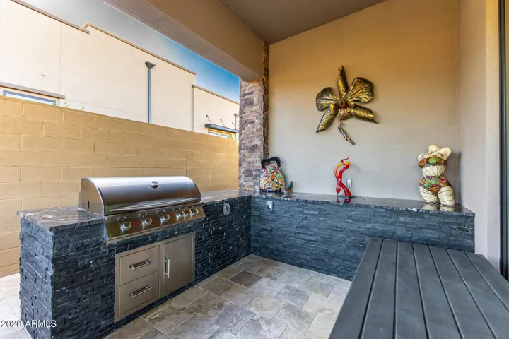 Outdoor kitchen with L Shaped granite island and stone pavers.