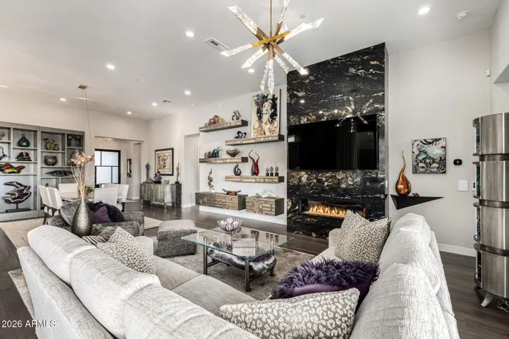 Great room with gas operated fireplace. Custom marble paneling and designer shelves accent this room.