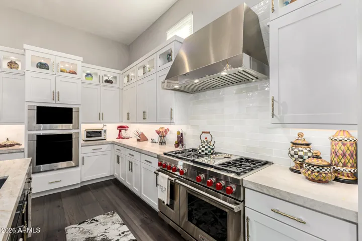 3 ovens, microwave, commercial grade vent hood, 42" box cabinets with glass fronts for display.