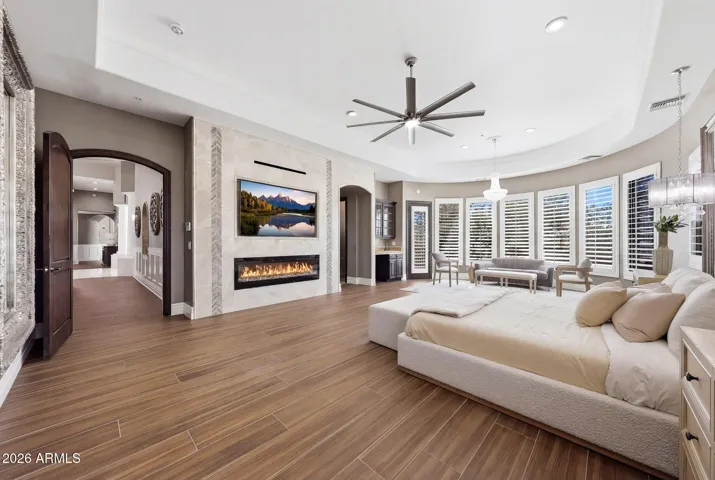 Expansive primary bedroom complete with sitting area, fireplace and plantation shutters