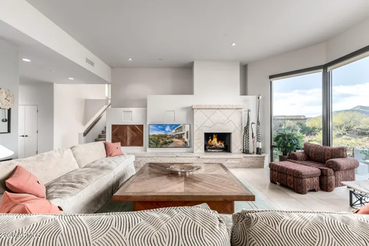 The seamlessly flowing living & dining room is paired with a fireplace and floor to ceiling windows.