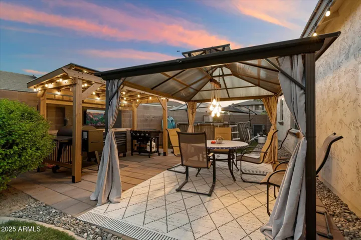 Enjoy resort-style living with a spacious gazebo, outdoor kitchen setup, and stylish paver patio. Designed for entertaining, this Peoria backyard also includes string lighting and ample seating space, enhancing the home’s indoor-outdoor flow.