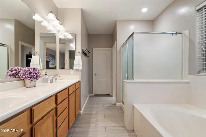 This well-appointed primary bathroom features dual sinks, expansive counter space, updated lighting, and a separate soaking tub and shower. Neutral finishes and tile flooring complement the clean, move-in-ready condition of this Peoria property.