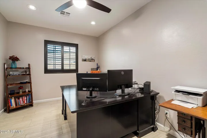 Configured as a home office, this space offers ample room for desks, shelving, and productivity. With energy-efficient lighting and neutral finishes, it can easily convert to an additional bedroom in this Peoria home.