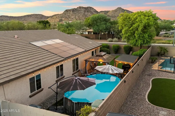 An aerial perspective showcases rooftop solar panels for energy efficiency, the private backyard pool, gazebo, and outdoor entertaining areas. This Peoria home combines sustainability with resort-style amenities.