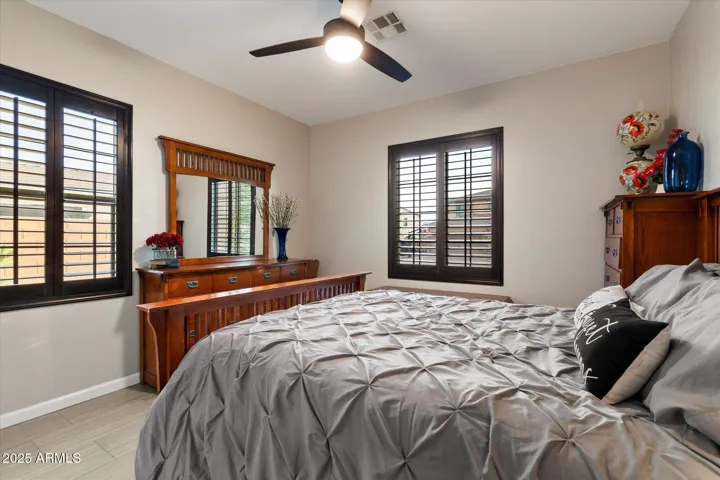 This secondary bedroom features plantation shutters, neutral finishes, tile flooring, and a ceiling fan for comfort. Ideal for guests or family members, the room complements the updated interior of this Peoria property.