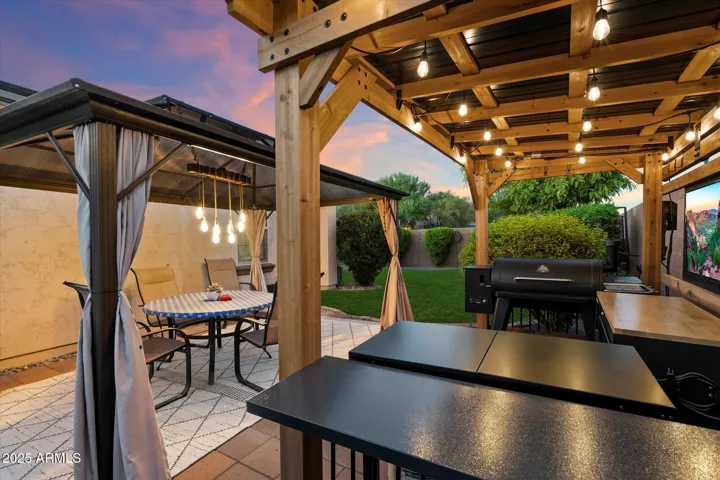 Experience resort-style living in this Peoria backyard featuring a sparkling pool, pergola with string lighting, covered seating area, and professionally designed landscaping. Artificial turf and paver patios create low-maintenance outdoor living spaces ideal for gatherings and Arizona evenings.