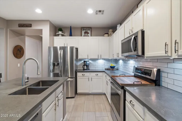 This beautifully updated kitchen in Peoria features crisp white cabinetry, sleek quartz-style countertops, stainless steel appliances, and a modern subway tile backsplash. Recessed lighting and under-cabinet illumination enhance the space, while the spacious layout offers both style and functionality—perfect for everyday living and entertaining.