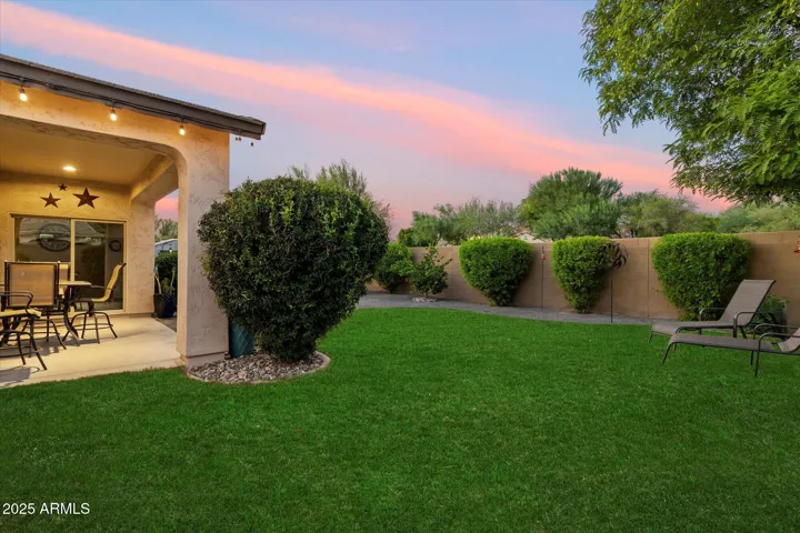 This spacious backyard showcases a lush lawn, covered patio, and mature trees for shade and privacy. With room for entertaining, play, or relaxation, this Peoria property delivers both comfort and versatility outdoors.
