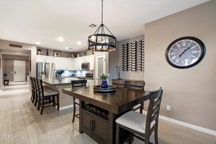 This expansive kitchen island includes a dual-basin sink, stainless steel dishwasher, and ample seating. Complemented by white cabinetry, subway tile backsplash, and energy-efficient recessed lighting, the space is both practical and stylish.