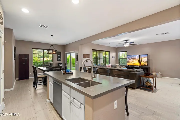 This beautifully designed kitchen includes an extended island with bar seating, updated countertops, recessed lighting, and stainless steel appliances. The open layout enhances the connection to the living and dining spaces, creating a functional and welcoming environment.