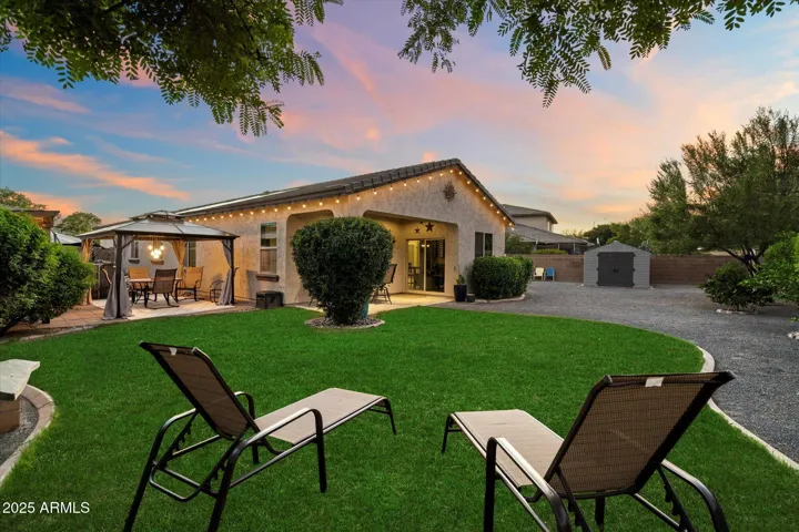 Designed for gatherings, this backyard features a green lawn, cozy seating areas, and a covered patio with lighting. The thoughtful landscaping and open space make this Peoria home ideal for year-round outdoor enjoyment.