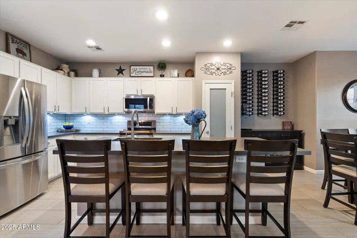This open kitchen design showcases an oversized island with ample seating, stainless steel appliances, and sleek countertops. The adjacent dining area and modern lighting fixtures create an inviting atmosphere perfect for gatherings and daily living in Peoria.