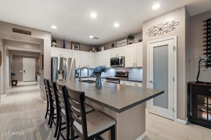 Featuring crisp white cabinets, a subway tile backsplash, stainless steel appliances, and a convenient pantry, this Peoria kitchen blends storage and style. The large island provides additional prep space and seating, ideal for entertaining and meal preparation.