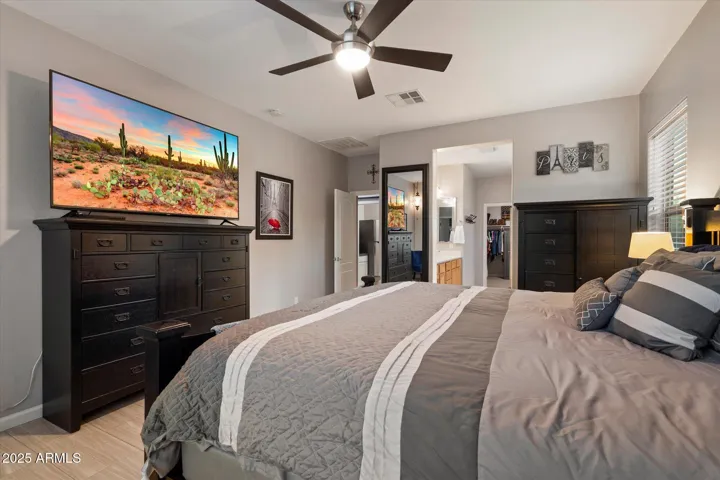 The spacious primary suite offers backyard views, modern ceiling fan lighting, and seamless access to the en-suite bathroom and walk-in closet. Designed for comfort and functionality, this Peoria home blends style and thoughtful layout throughout.