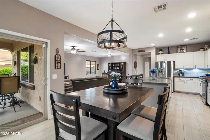 The dining area features a striking modern chandelier and direct access to the covered patio, promoting seamless indoor-outdoor living. Positioned adjacent to the updated kitchen, this Peoria home offers an ideal setup for entertaining and comfortable everyday use.