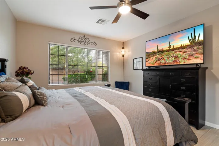 This inviting primary bedroom in Peoria features neutral tile flooring, a ceiling fan for energy efficiency, and large windows overlooking the private backyard. The generous layout easily accommodates full furnishings and offers direct access to the en-suite bath, creating a comfortable retreat within the home.