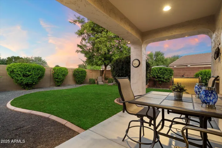 This inviting backyard in Peoria features a covered patio perfect for outdoor dining, a manicured green lawn, and mature landscaping for added privacy. Ideal for entertaining or relaxing, this outdoor space complements the home’s open layout and move-in-ready condition.