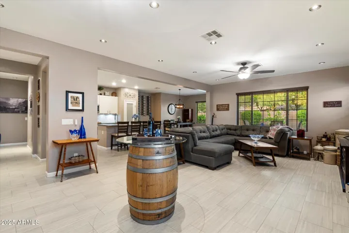 The bright great room design features modern recessed lighting, ceiling fan, and wide windows overlooking the backyard oasis. With its open-concept layout and updated finishes, this Peoria home provides ideal space for relaxing or entertaining.