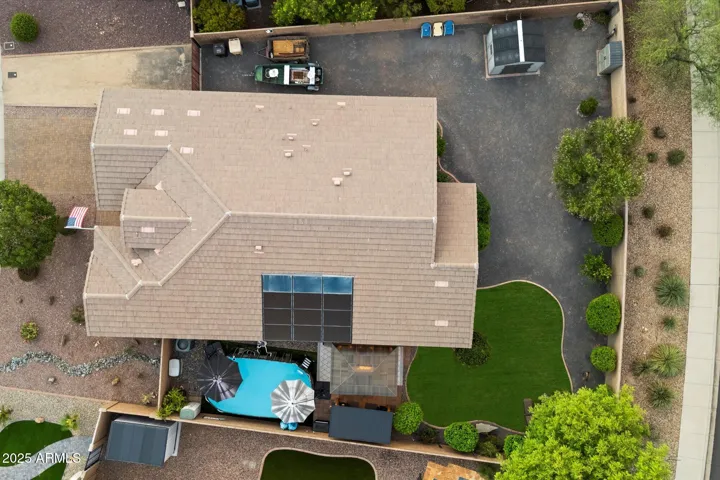 This overhead drone shot highlights the home’s roofline, solar panel system, backyard pool, lawn, and additional gravel parking area. A well-designed outdoor layout enhances functionality and value in this Peoria property.