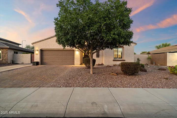 This inviting Peoria home showcases attractive desert landscaping, a paver driveway, and a spacious two-car garage. Warm exterior lighting and mature trees enhance the curb appeal, while the low-maintenance design complements Arizona living.